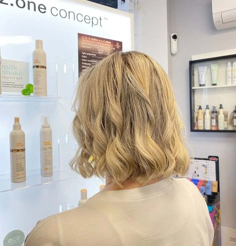 Piega su capelli biondi realizzata in salone, vista di spalle